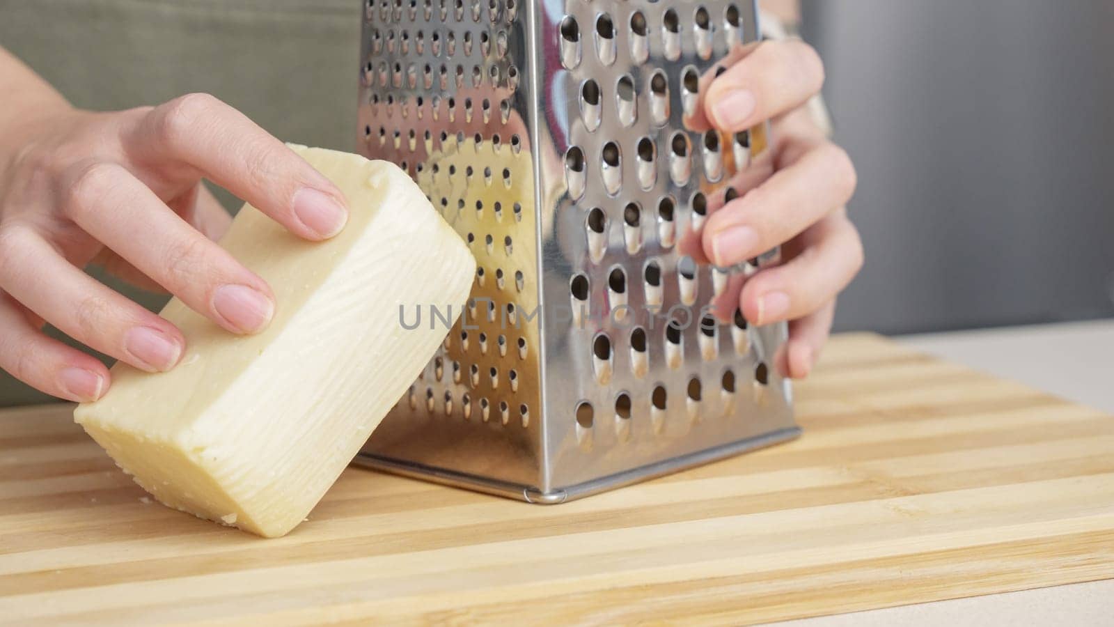 chef grating traditional parmesan cheese with steel grater on the wooden board.