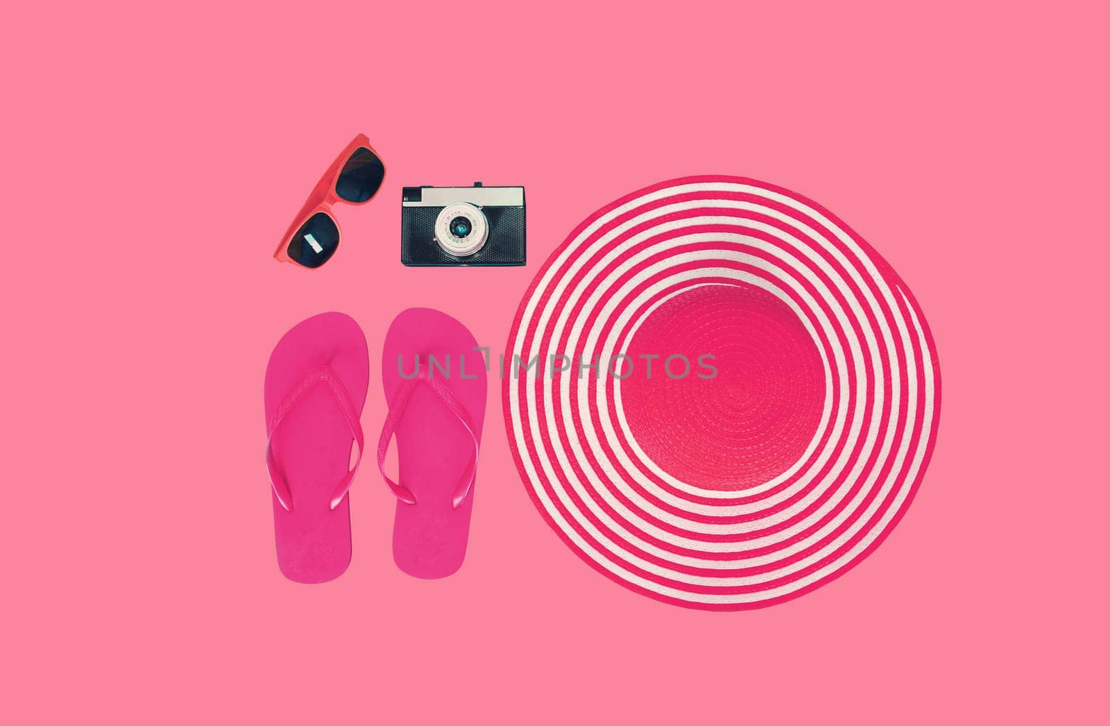 Summer vacation, straw beach hat with flip flops, film camera and sunglasses on pink background, view from above