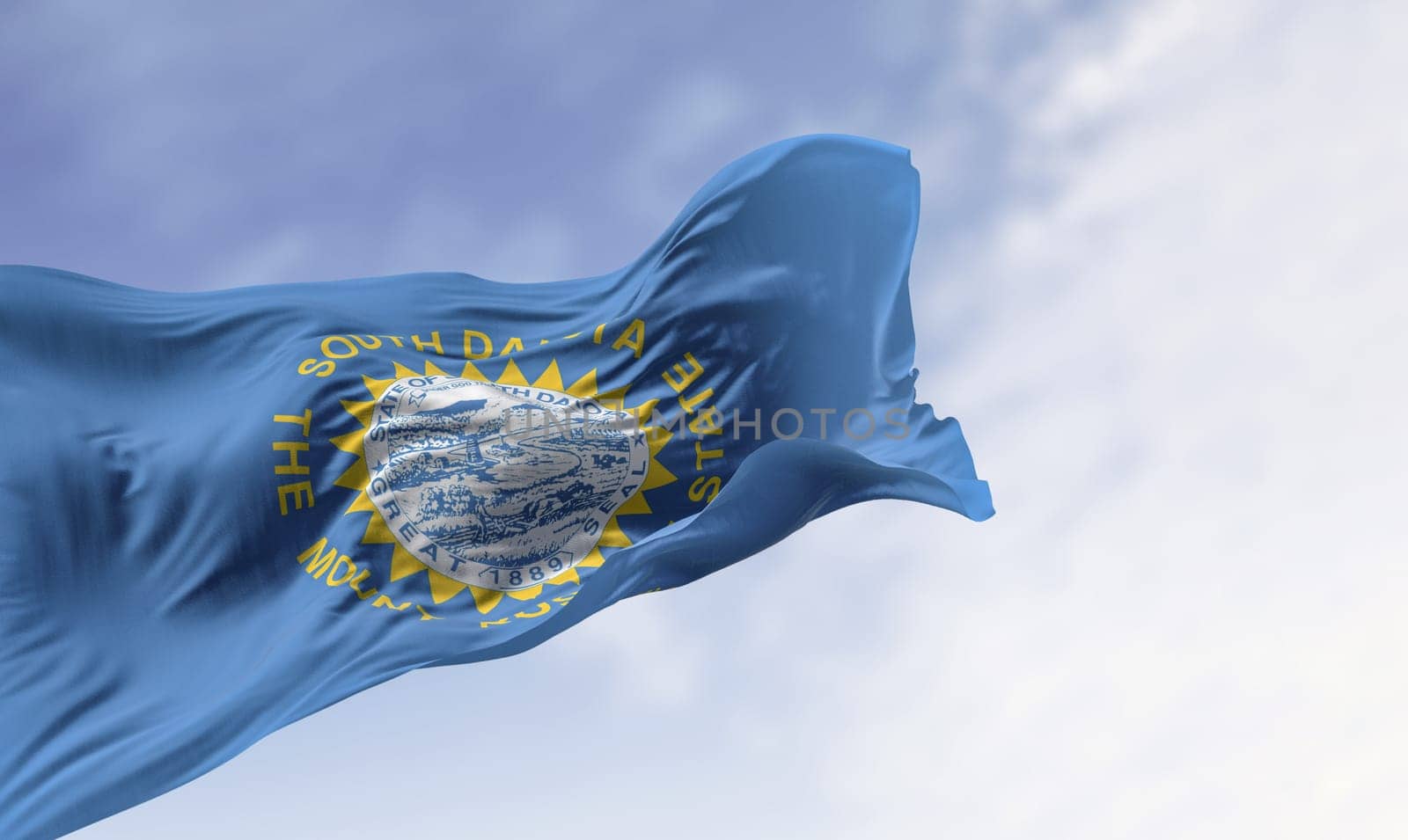 Close-up of the South Dakota flag with state seal fluttering in the wind, featuring sun rays symbolizing pride, freedom, and identity. Realistic 3D render of textured fabric