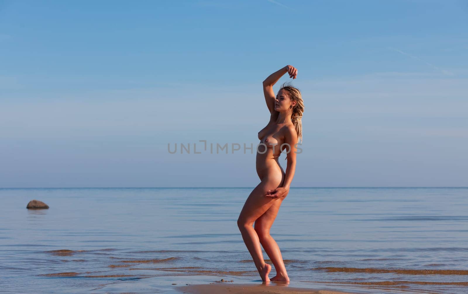 Young woman posing nude on the seaside on a summer afternoon