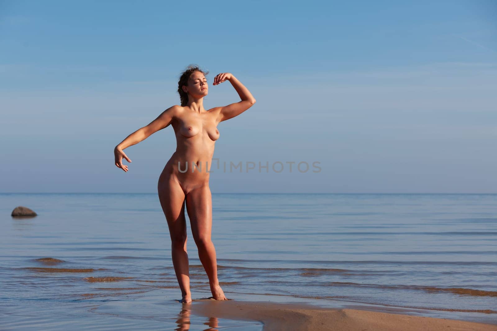 Young woman posing nude on the seaside on a summer afternoon