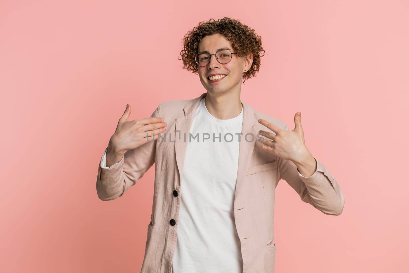 I am the best, choose me. Happy Caucasian man feeling very proud pointing himself, looking self-confident, overjoyed by success, making choice. Young guy isolated on studio pink background indoors