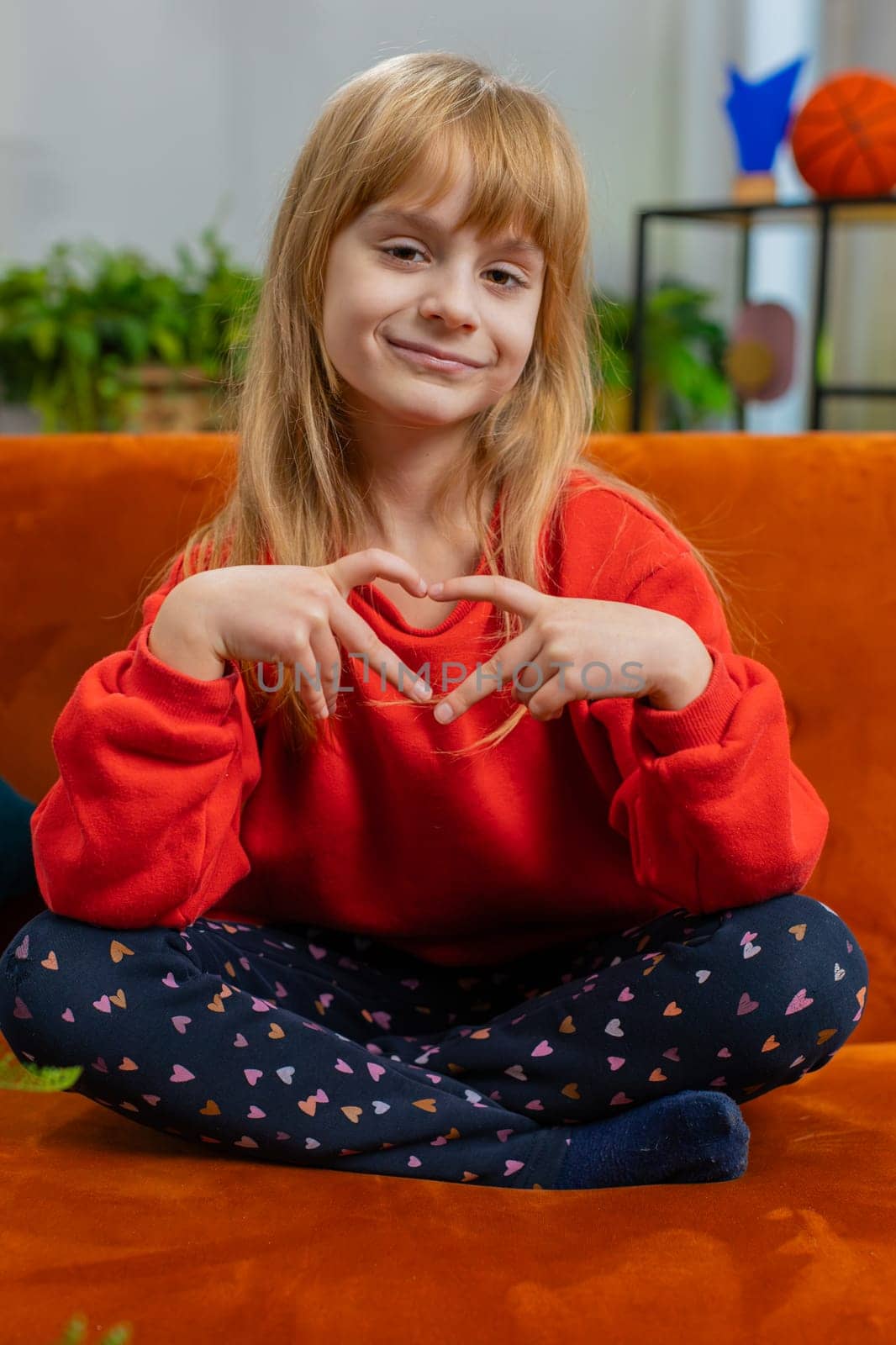 I love you. Child kid girl makes symbol of love, showing heart sign to camera, express romantic feelings, express sincere positive feelings. Charity, gratitude, donation. Female teen at home. Vertical