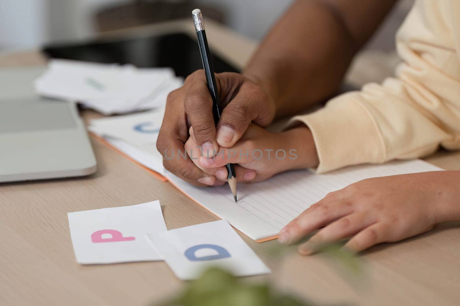 A father assists his son with a writing exercise during their homeschool session, emphasizing collaboration and learning in a homely atmosphere.