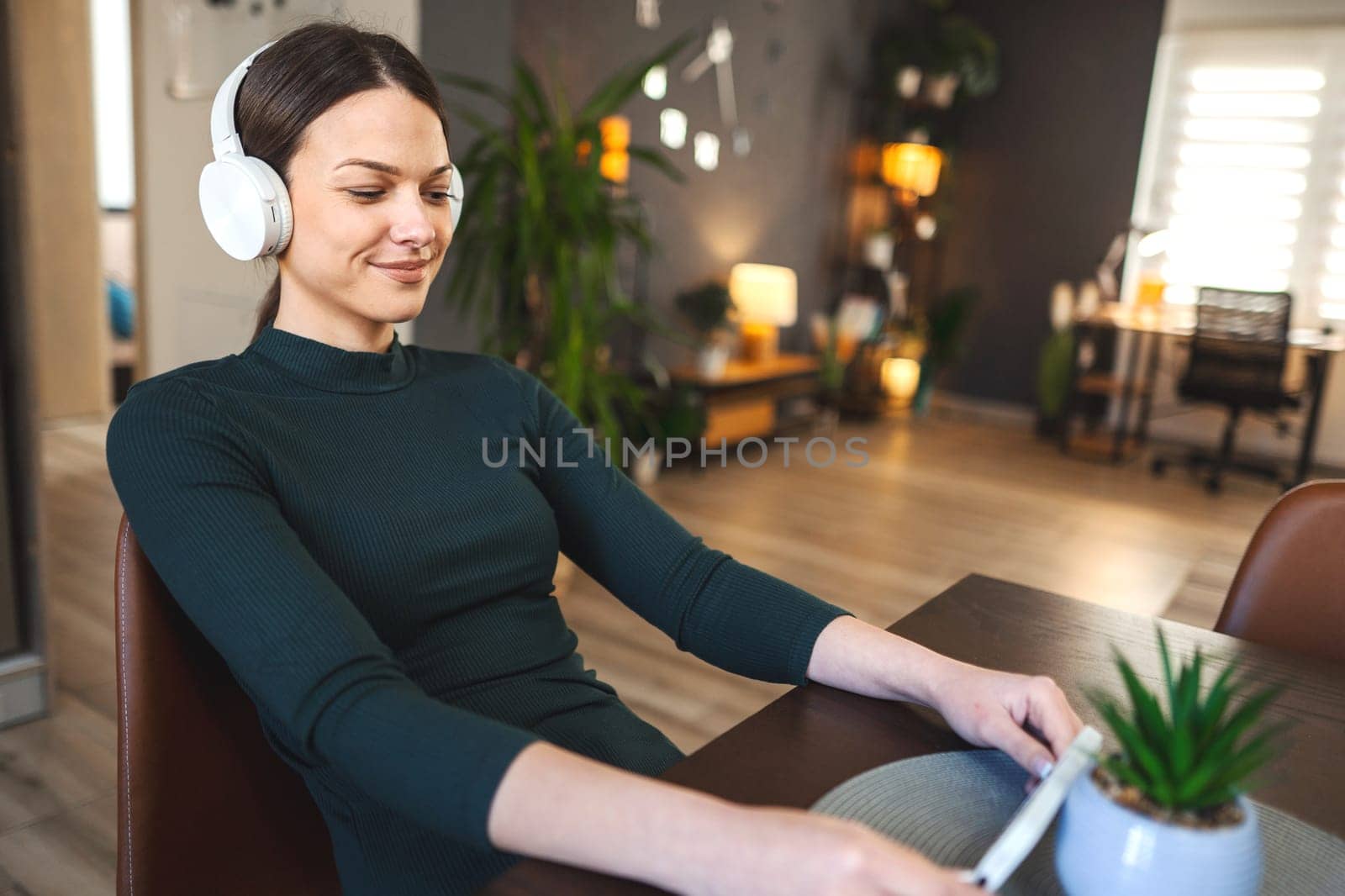 Very happy young girl with white headphones enjoy using a mobile phone indoor.