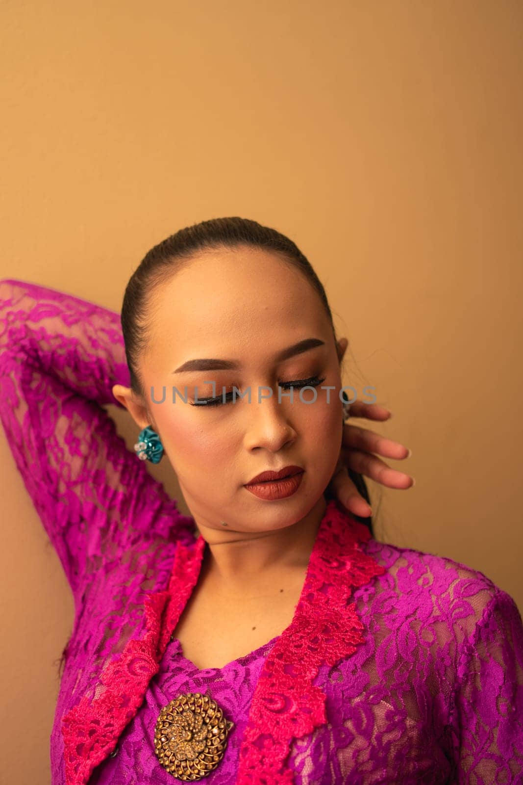 Asian woman touches her head while posing with makeup inside the studio