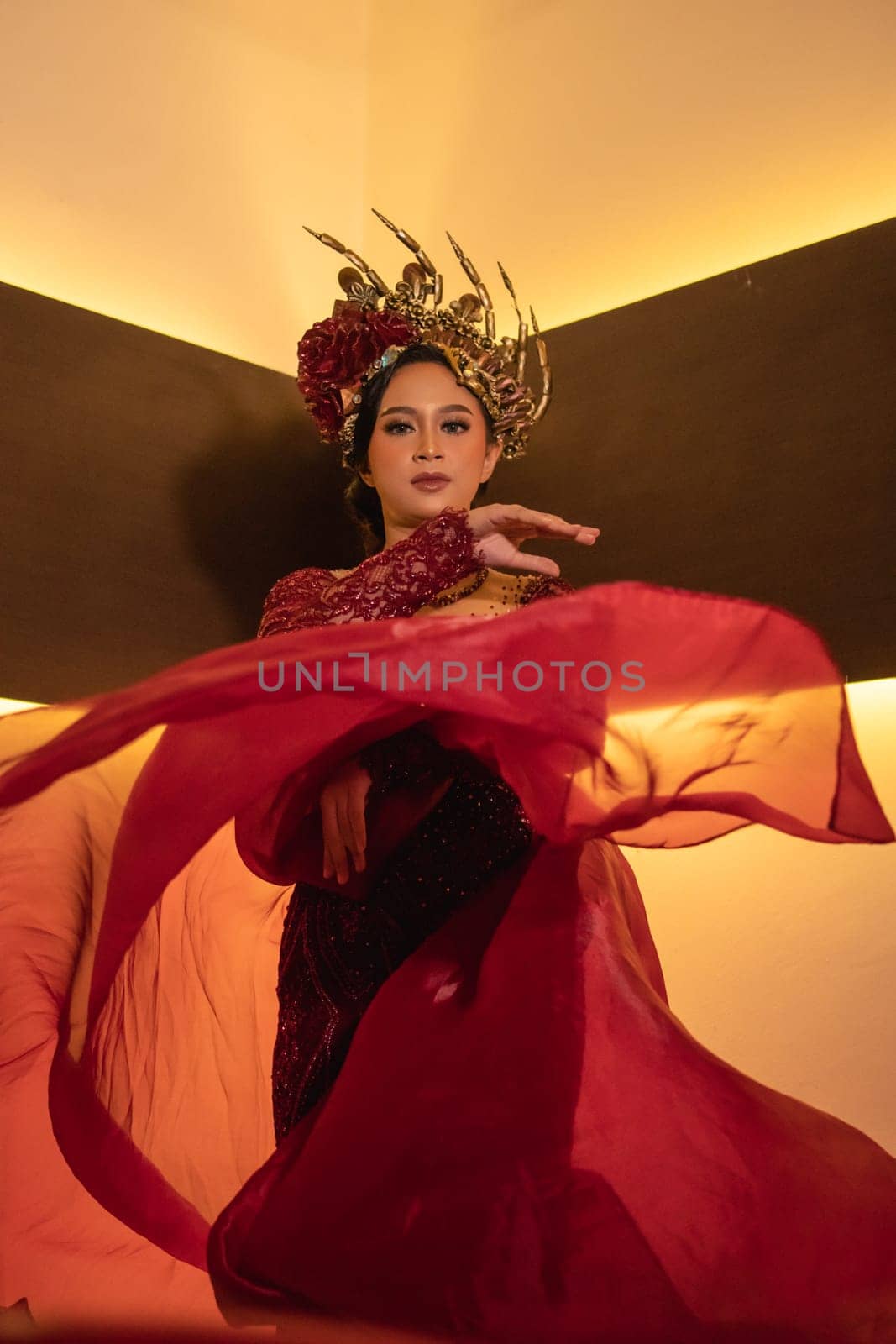 A beautiful Asian woman swings the red fabric tail while wearing a red wedding dress before the wedding ceremony