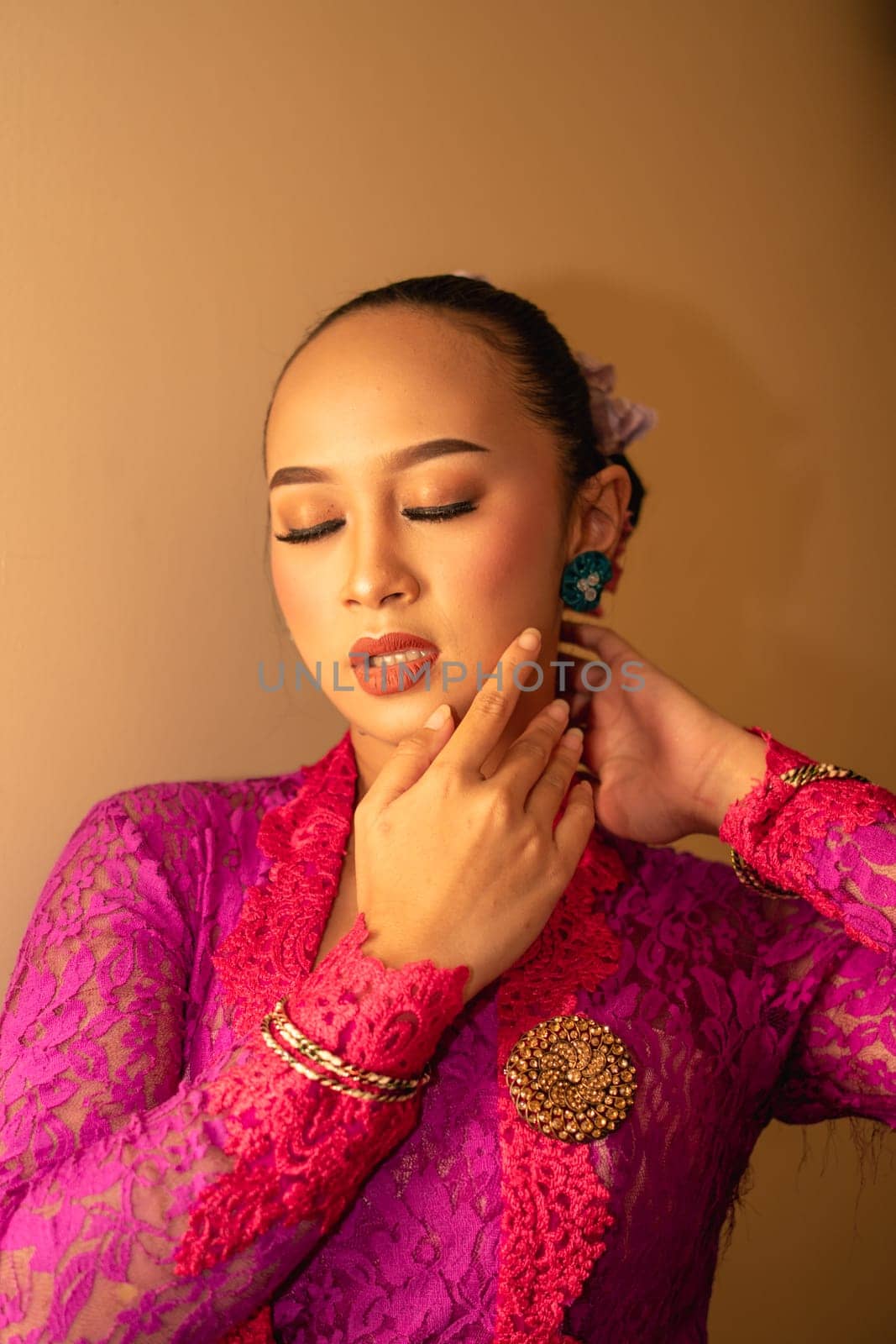 Asian woman touching her neck and feeling sexy with herself while posing inside the cream room