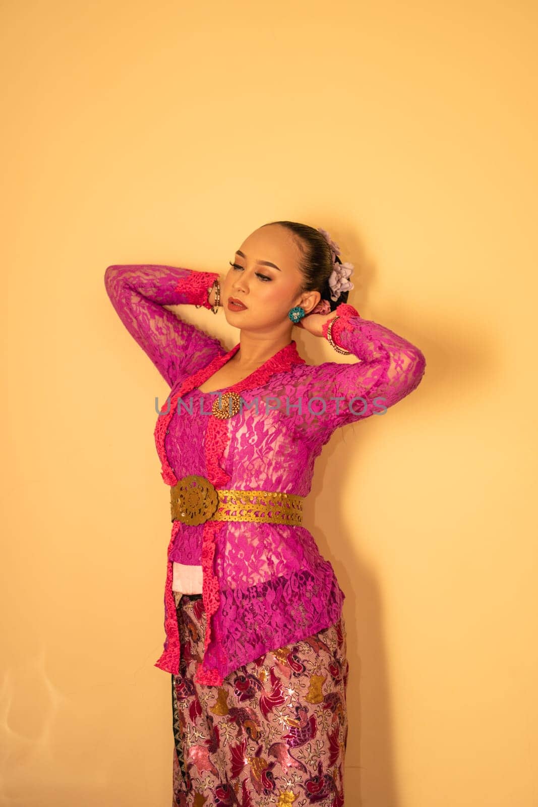 Balinese mother wearing a pink dress called kebaya and make-up before praying in the temple