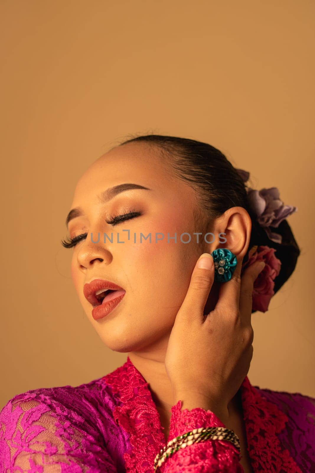 Sexy Asian woman wearing a pink dress called kebaya with a hot pose inside the studio