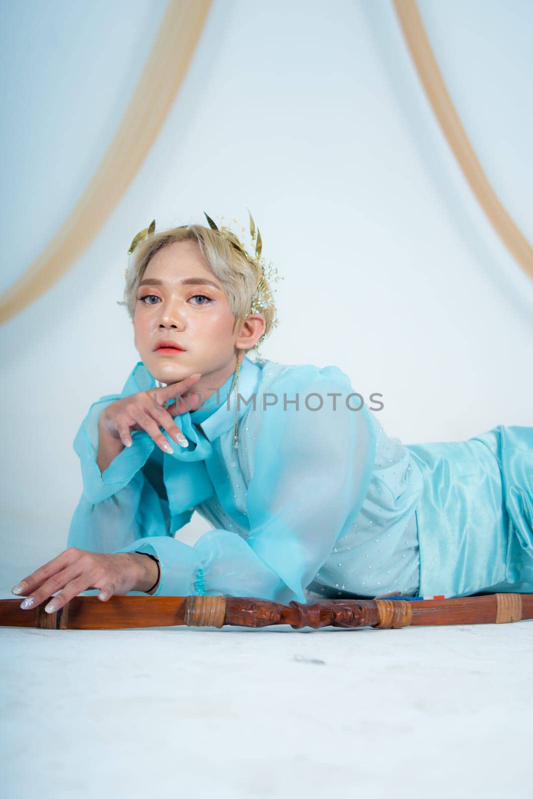 a princess in a blue dress posing on the floor with a bow in a white room