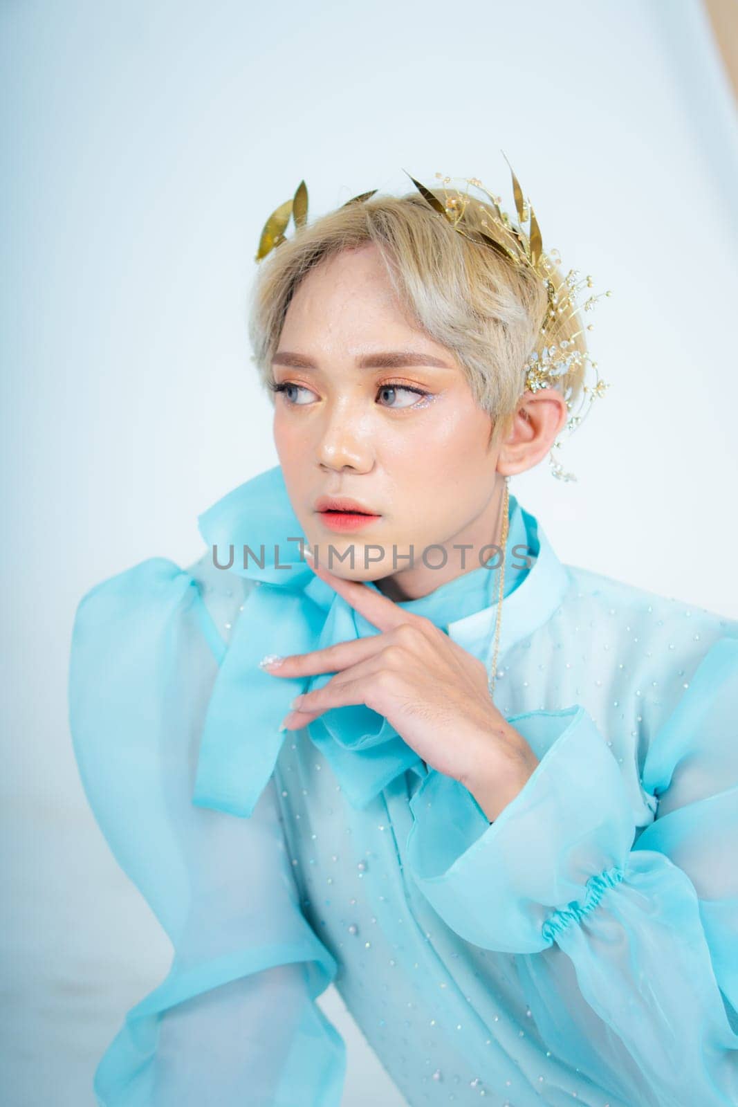 a royal princess posing with a golden crown and blonde hair very cutely in a white room
