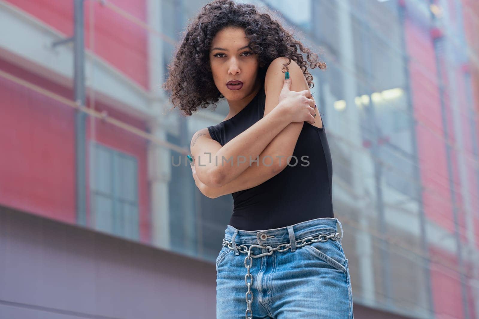 African American woman dancing in a creative pose between benches in an urban setting. She wears casual clothes and shows balance, strength, and expression. Concept of movement, art, and freedom.