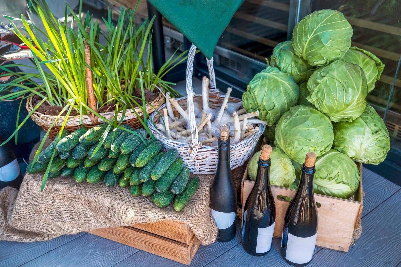 Fresh vegetable market. Cucumbers, garlic in a basket, wine, young greens. Healthy vegetarian ingredients for cooking. Various clean vegetables, Products from the market without plastic.