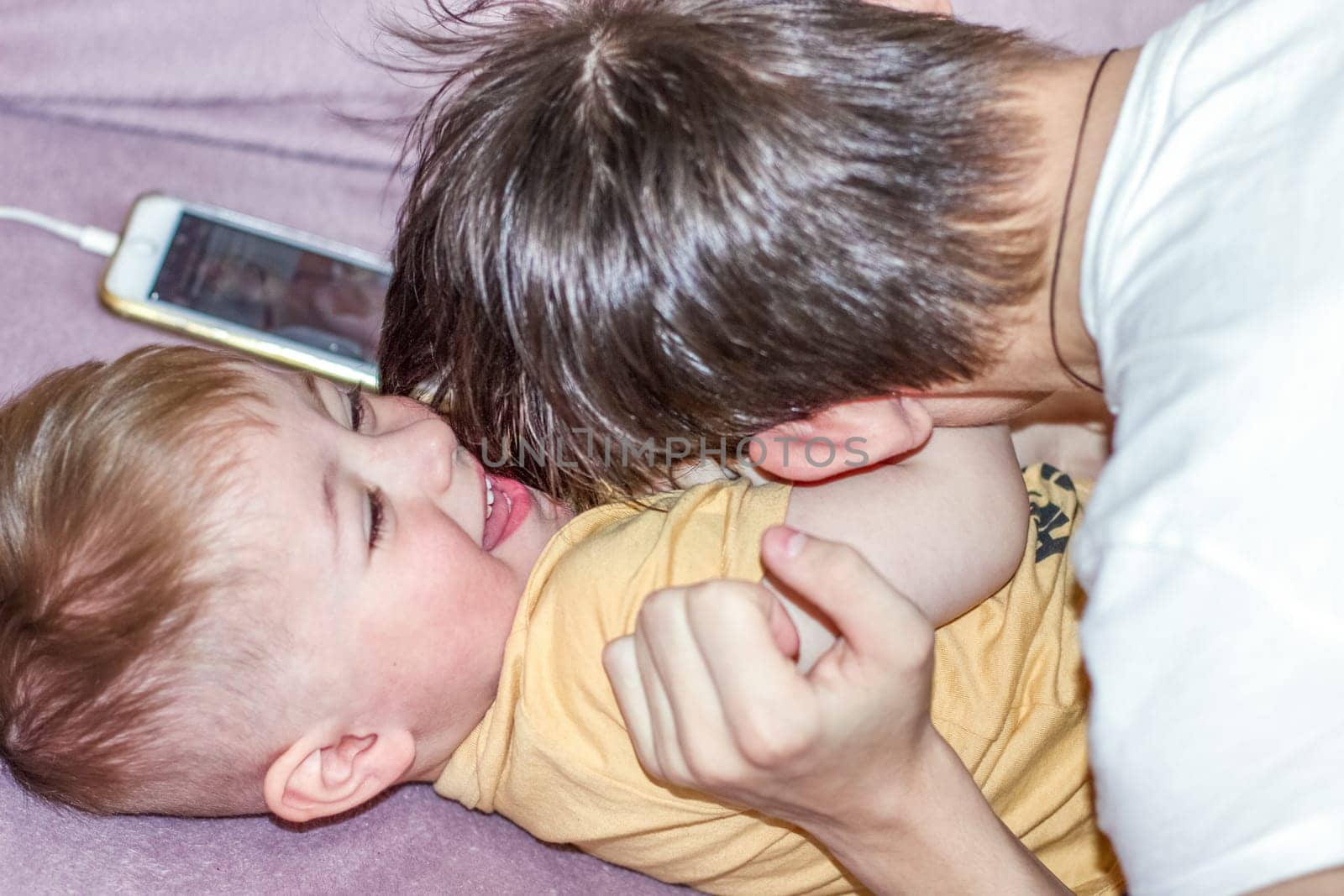 Teenage boy happily playing with his younger brother while looking after him. High quality photo