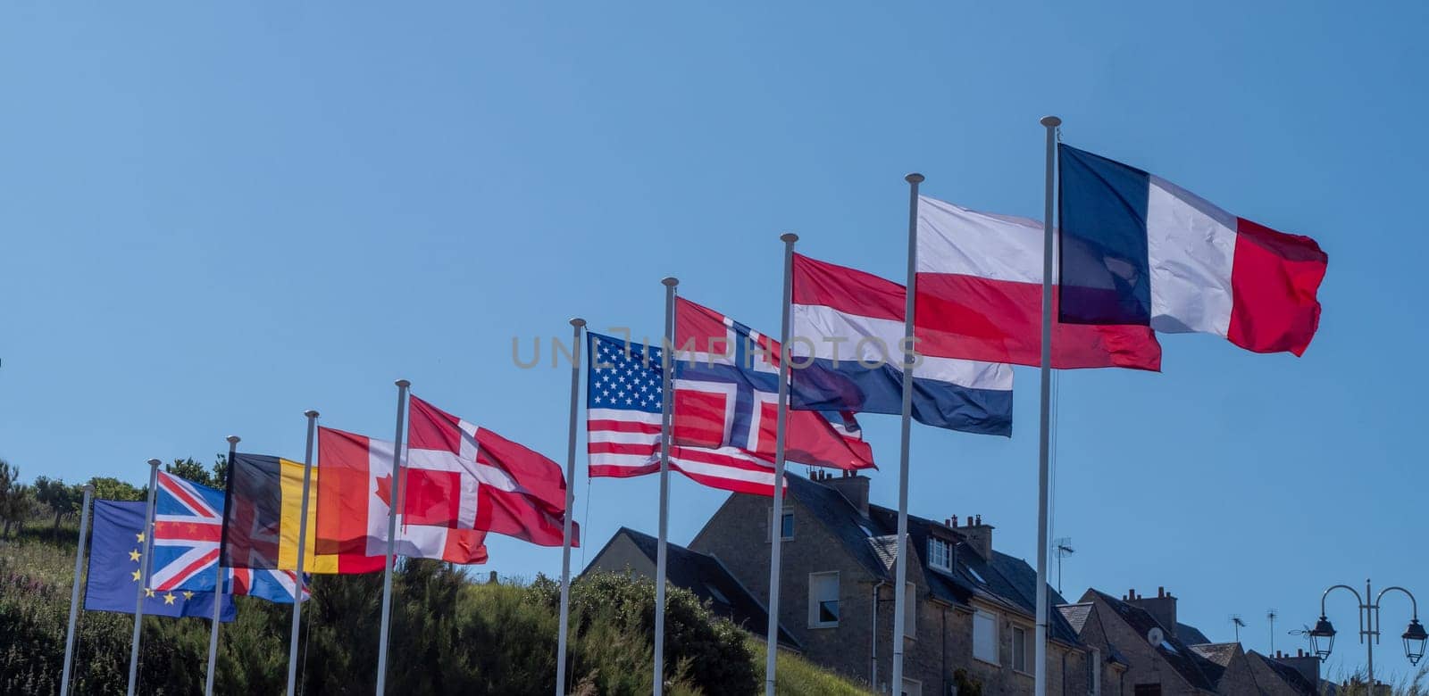 A row of flags from different countries are flying in the sky. The flags are of various sizes and colors, and they are arranged in a neat row. Concept of unity and diversity