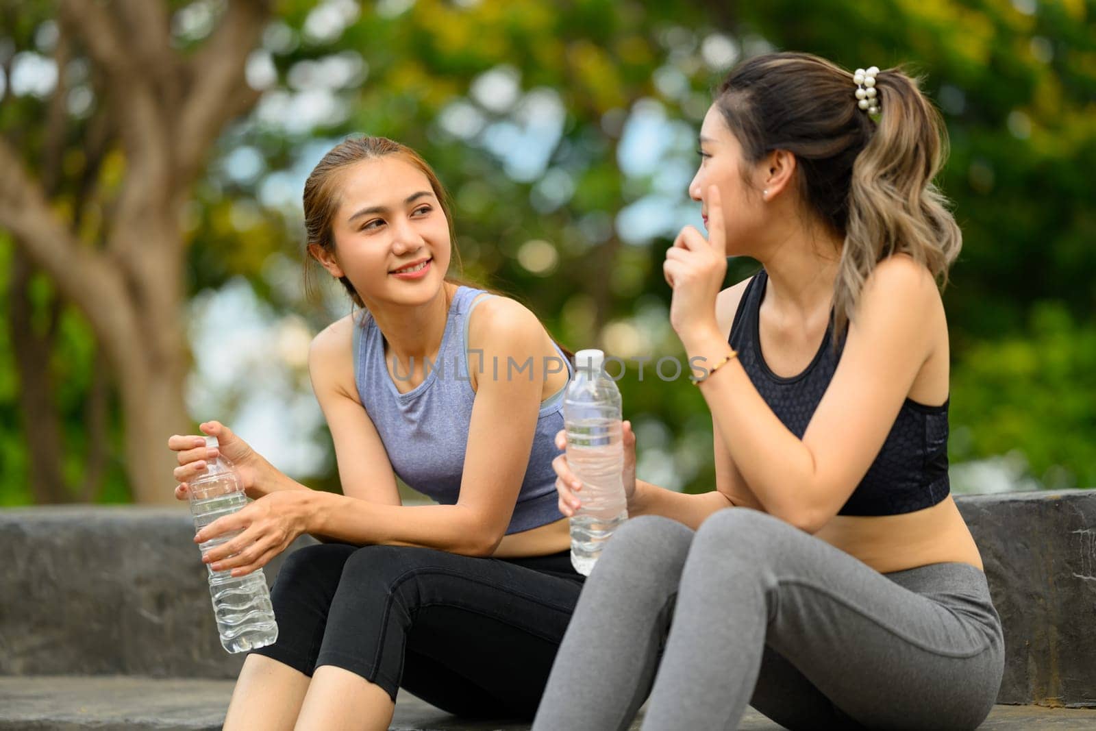 Female friends cooling down after exercise, enjoying conversation and hydration outdoors.