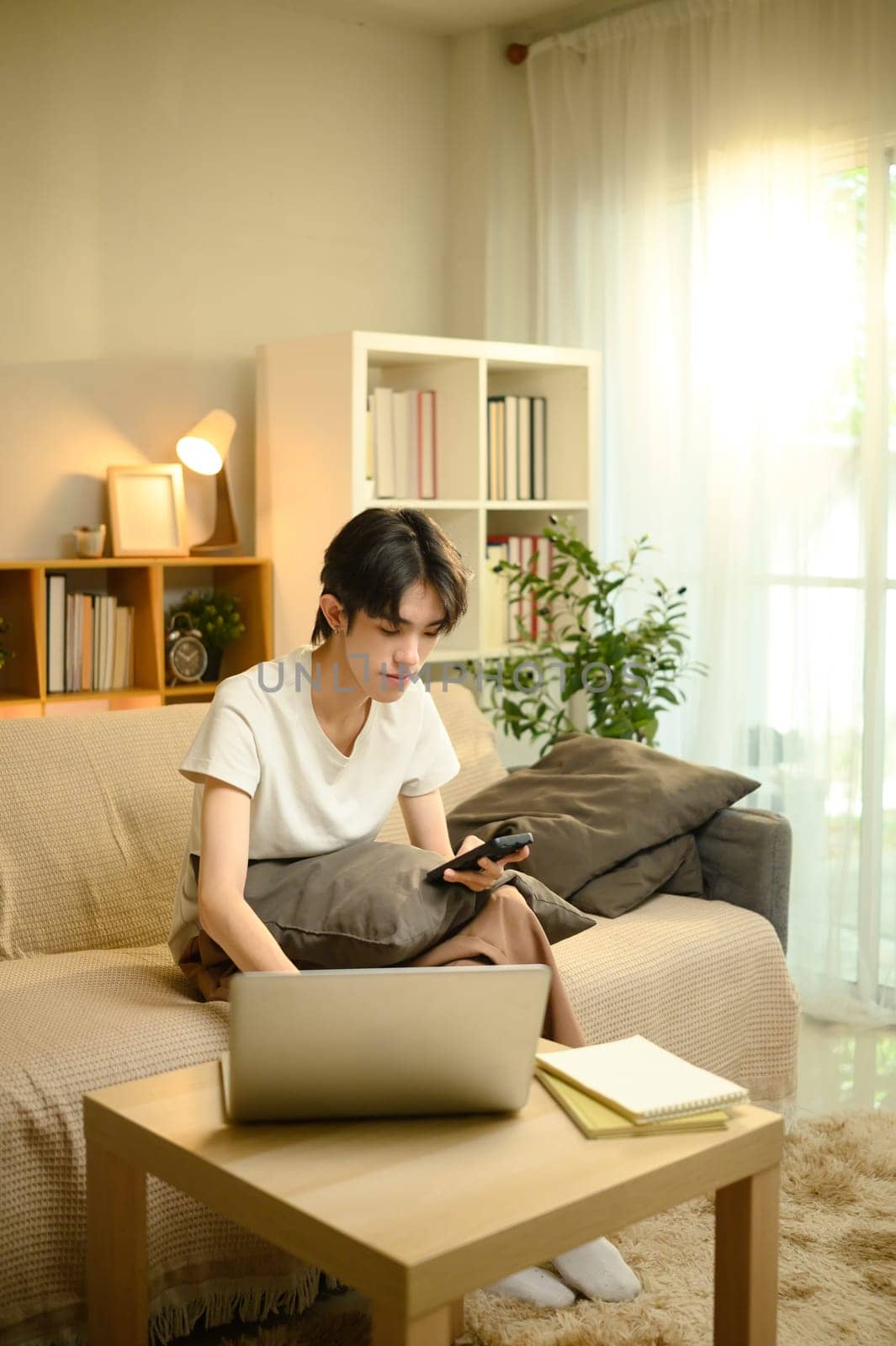 Relaxed man using technology for work or study in cozy living room.