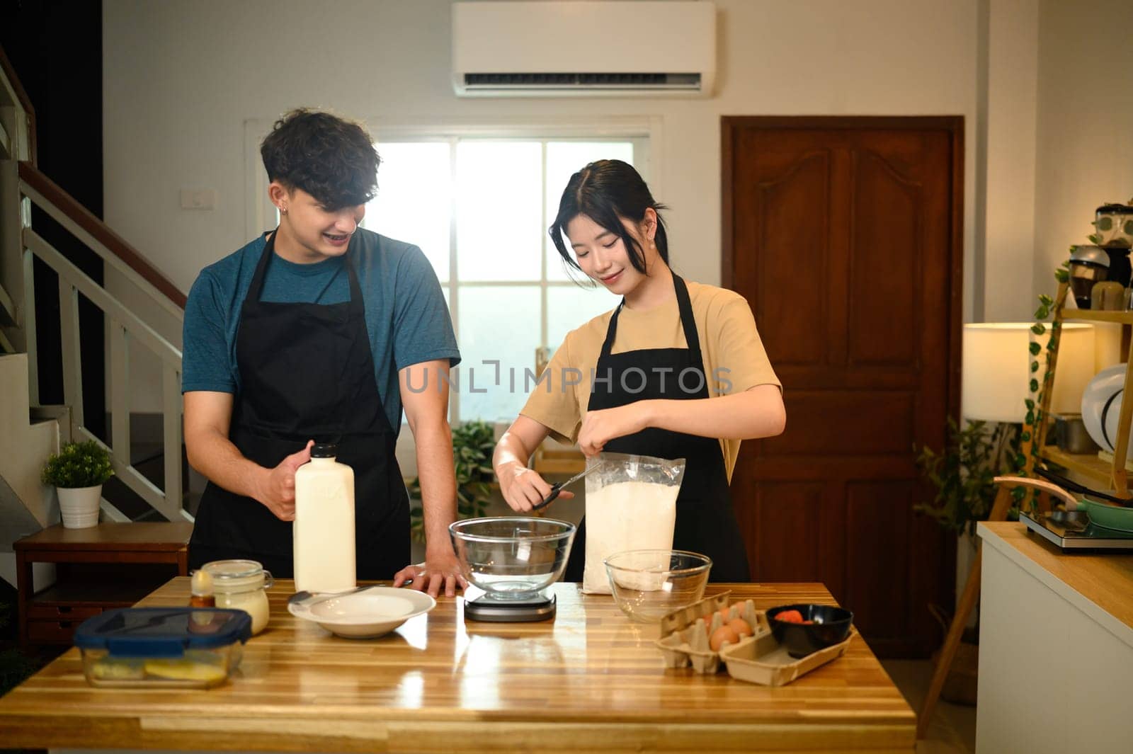 Couple cooking together preparing pancake mix with fresh ingredients.