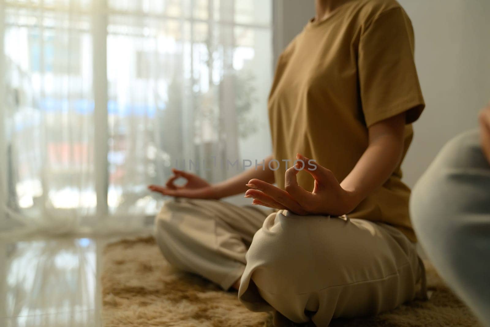 Peaceful young woman with curly hair practicing yoga at home.