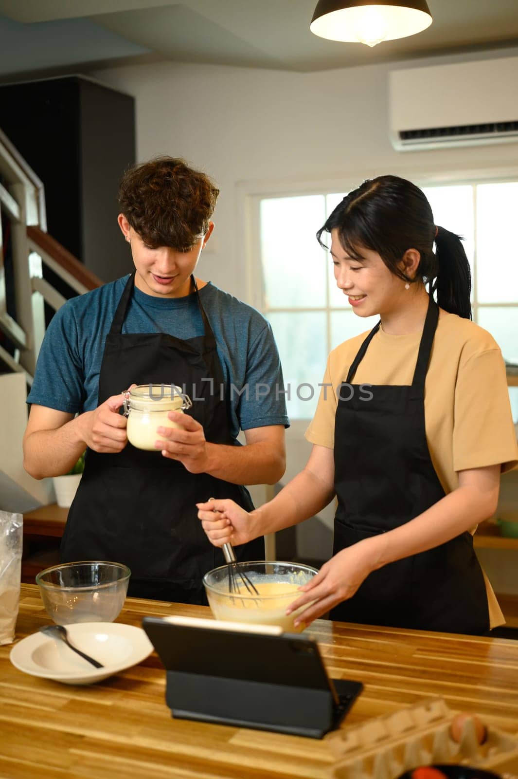 Young couple preparing pancake ingredients together in cozy kitchen.