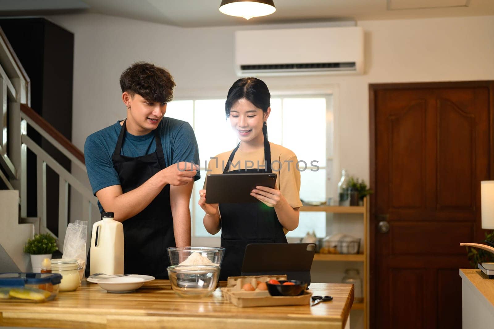 Happy man and woman following step by step pancake recipe together at home.