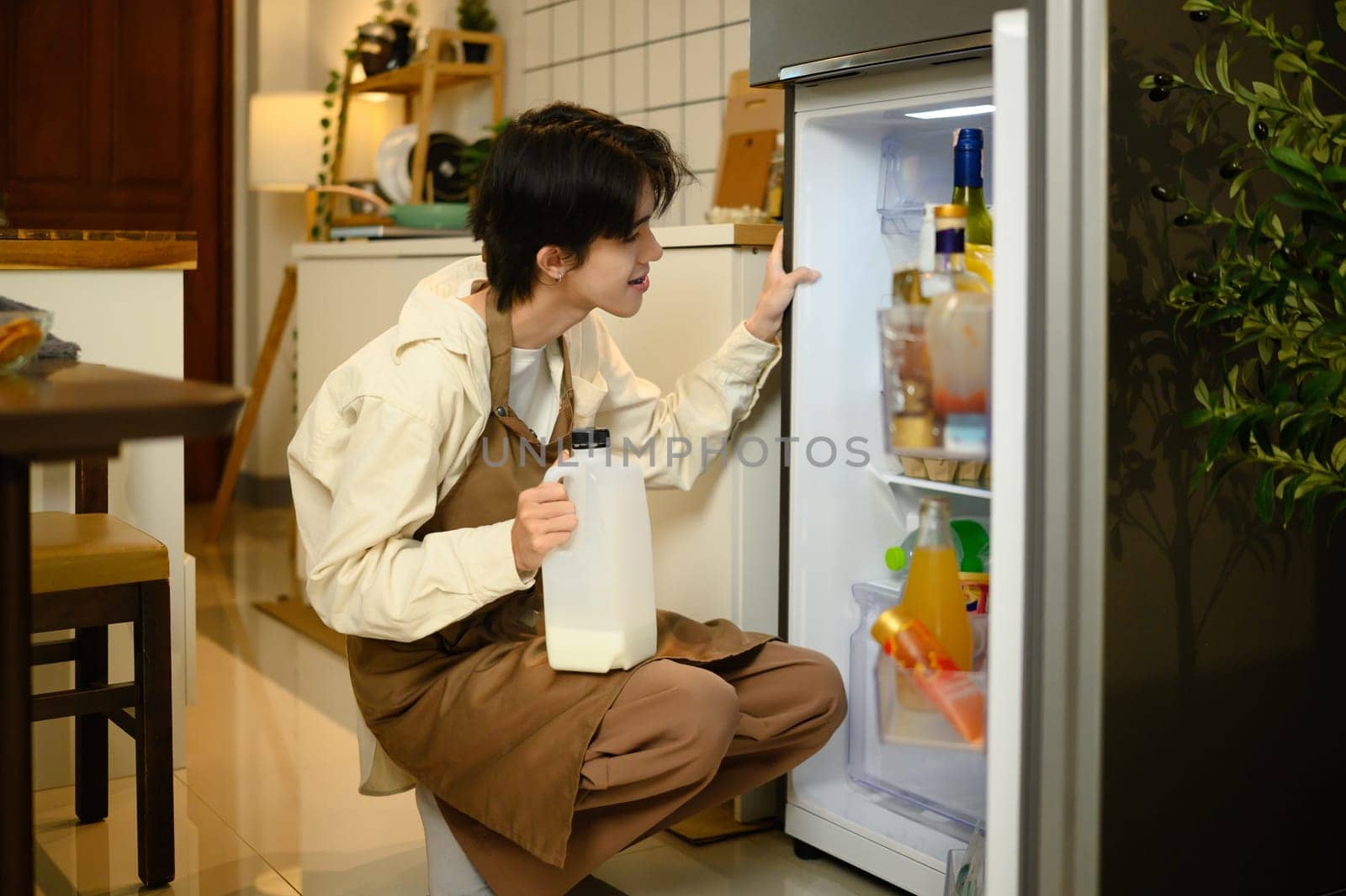Man taking milk from refrigerator in kitchen while preparing breakfast.
