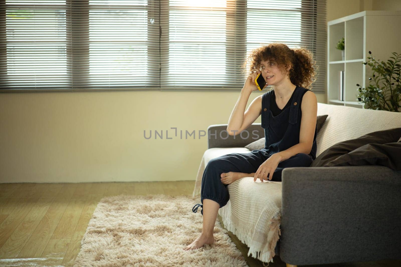 Relaxed woman enjoying a phone conversation in a cozy living room.