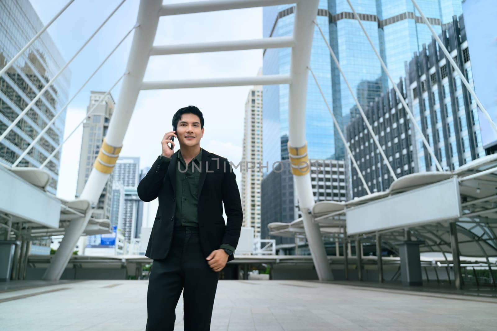 Successful businessman walking through a modern cityscape while talking on his phone.
