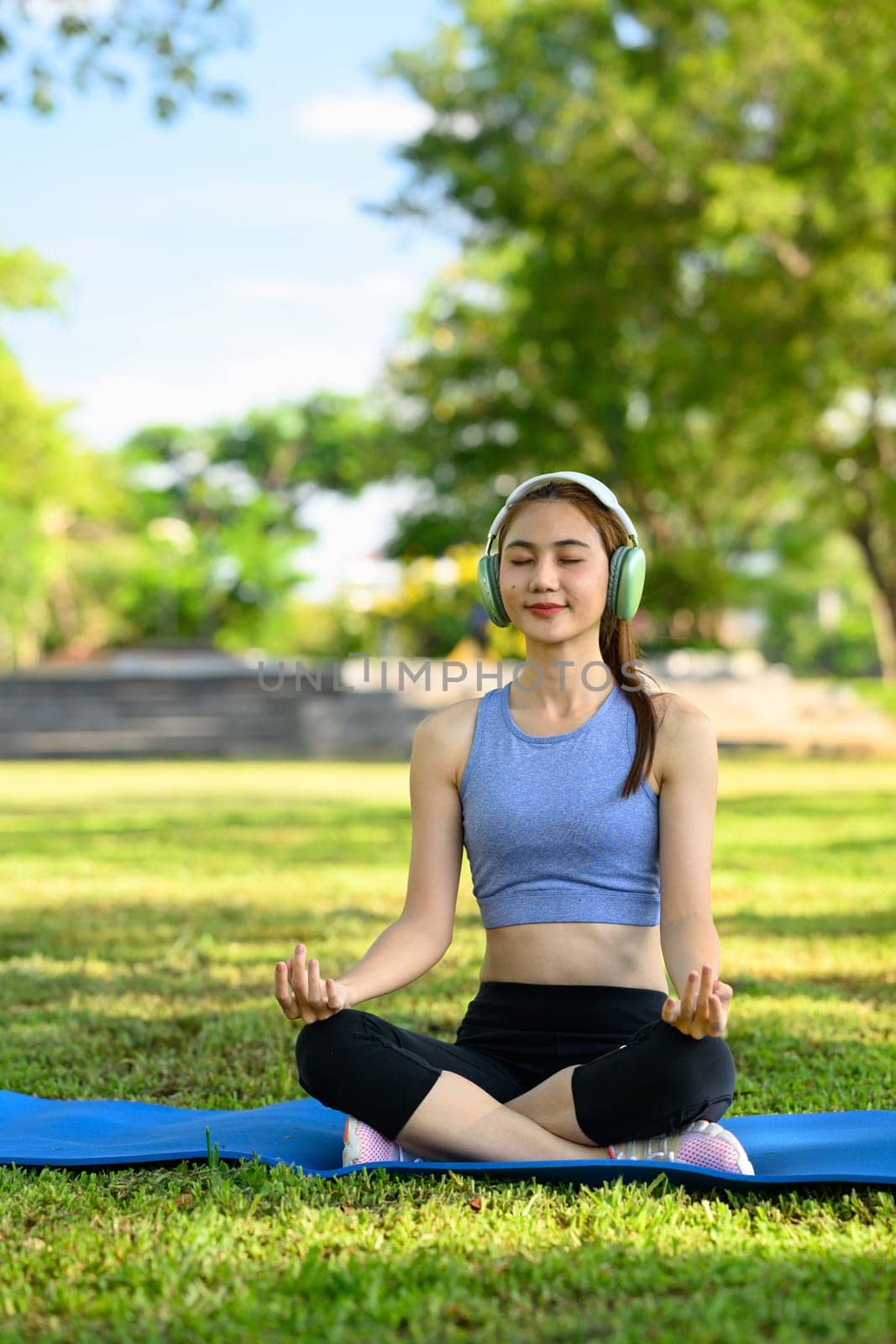 fit woman doing yoga and listening to music on headphones in the park.