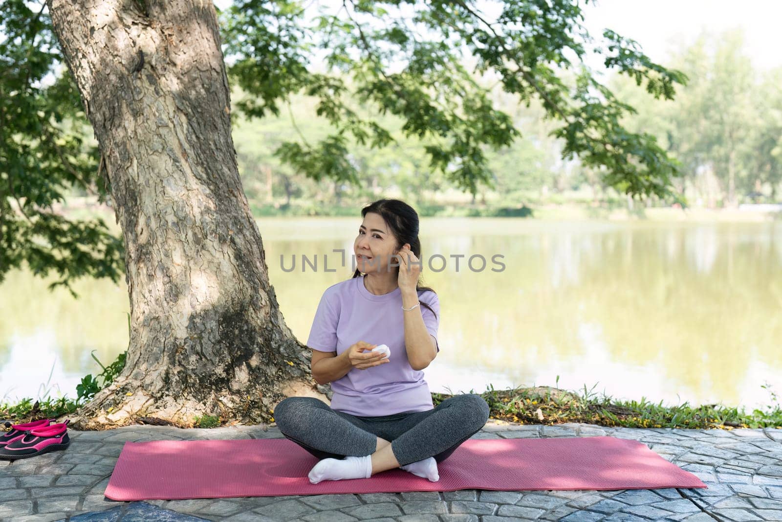 A woman practices mindfulness by the lake, enjoying a healthy snack, embodying wellness and self-care.
