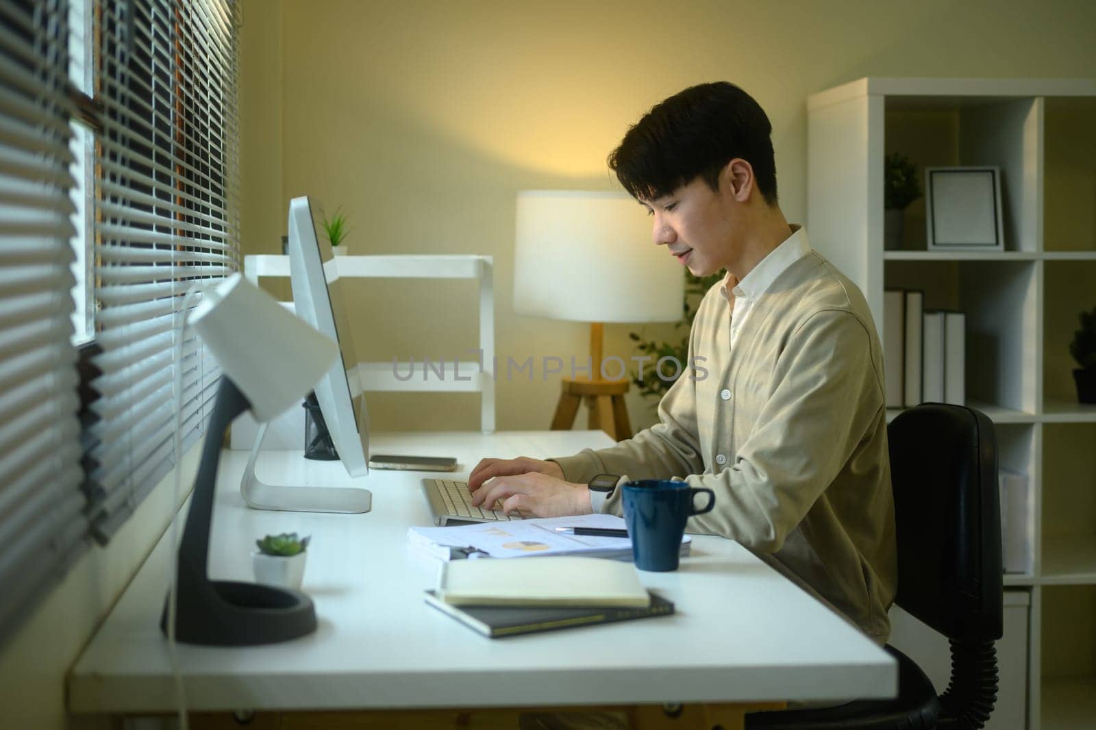 Smiling young man working from home at a bright modern desk.