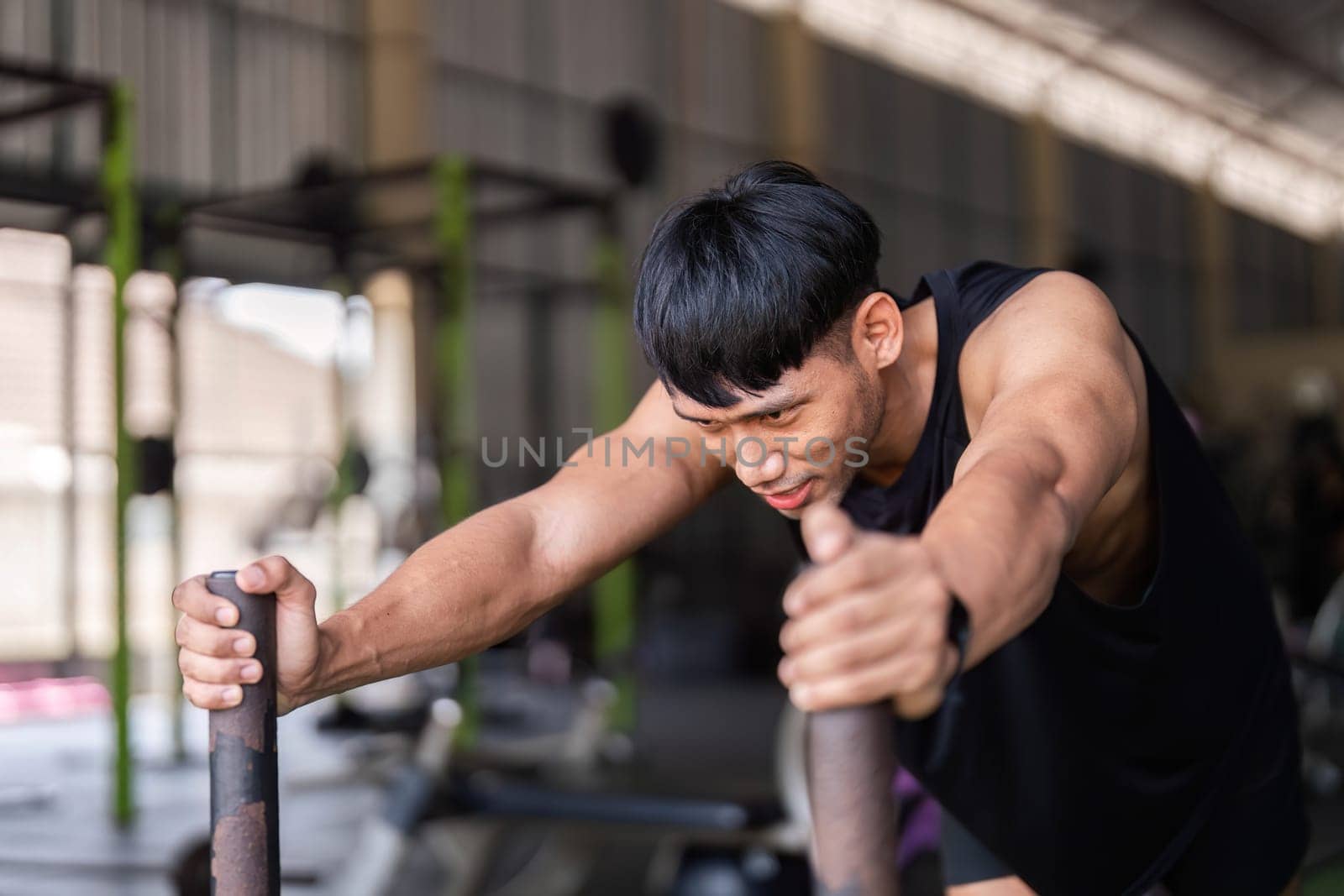 A determined man performs sled push exercise in a gym, emphasizing fitness and strength conditioning.