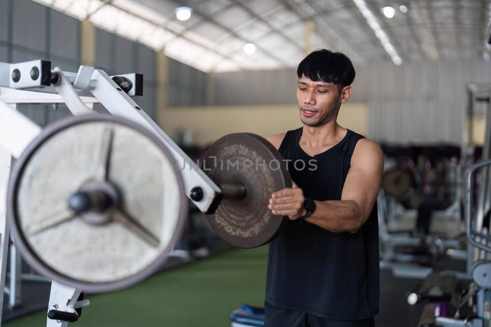 A dedicated male athlete focuses on lifting weights in a modern gym, showcasing strength training and fitness commitment.