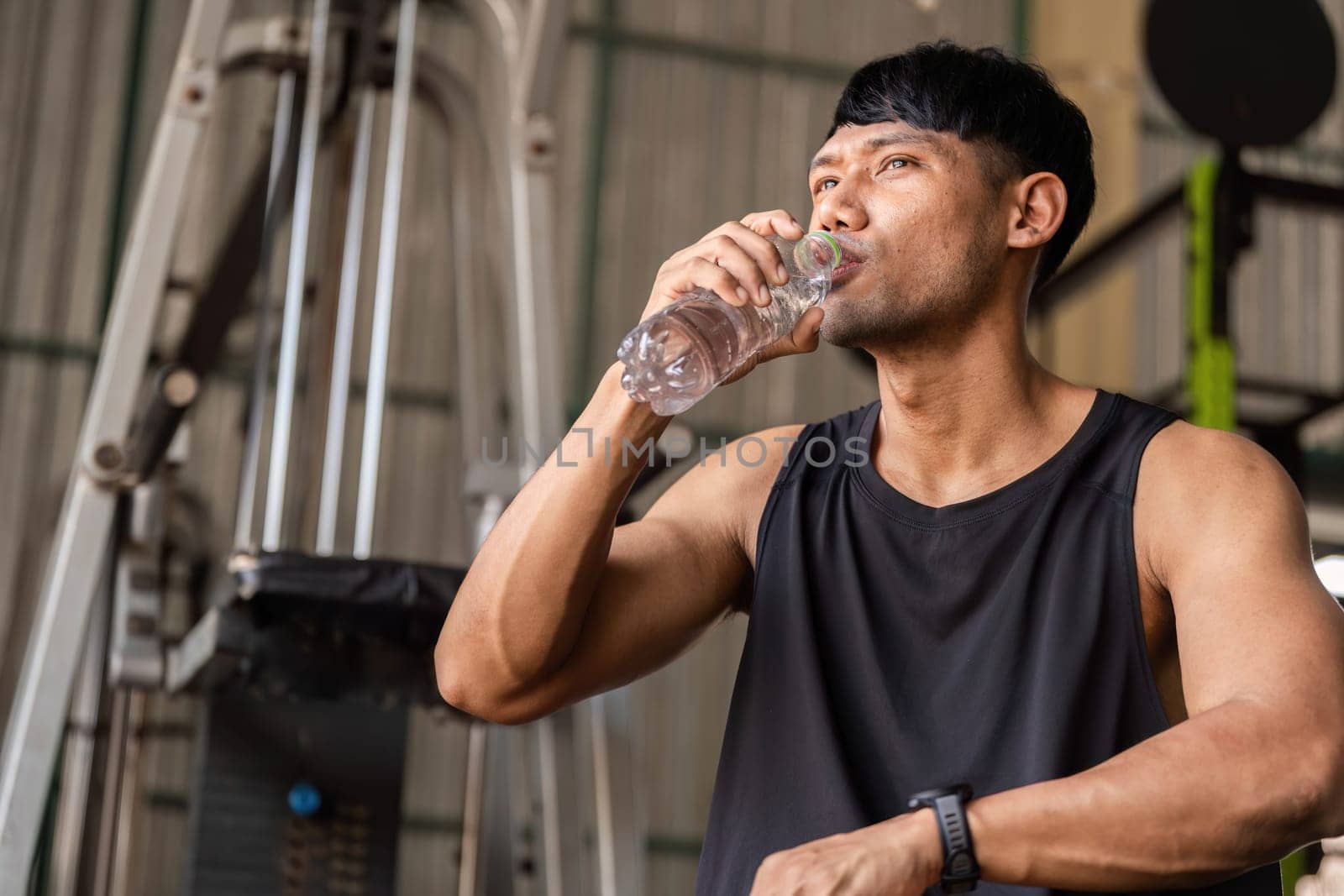 A dedicated athlete takes a break to drink water, highlighting hydration's role in fitness and health during workouts.