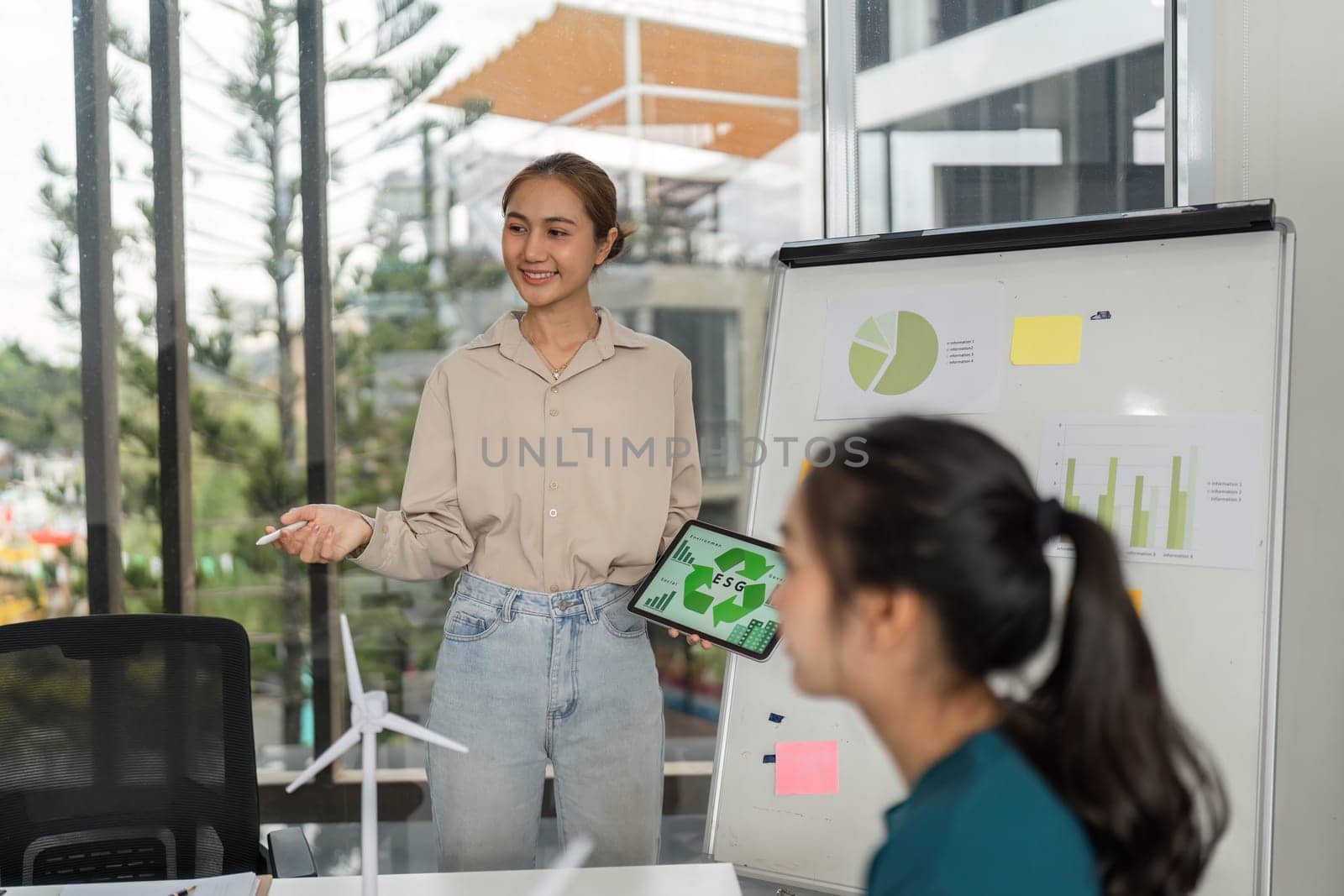 A young professional presents ESG data on a tablet during a business meeting, promoting sustainability and corporate responsibility.