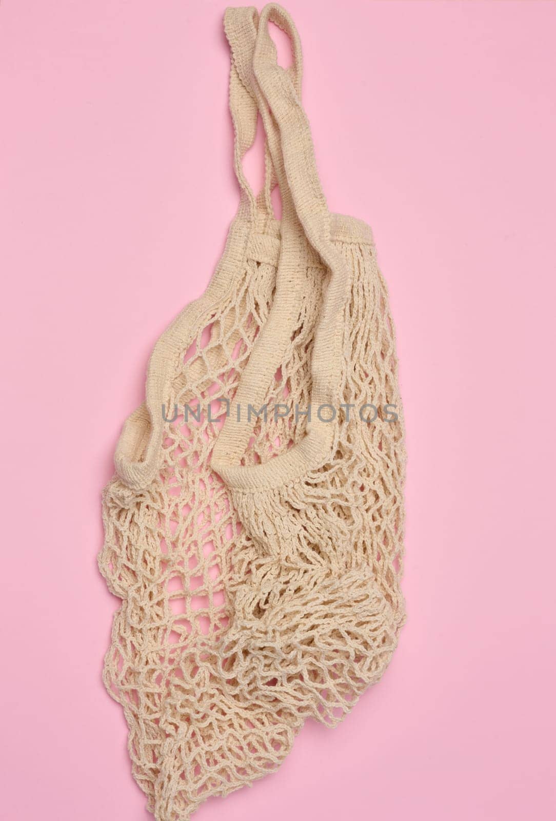 Empty reusable cotton mesh bag on pink background, top view