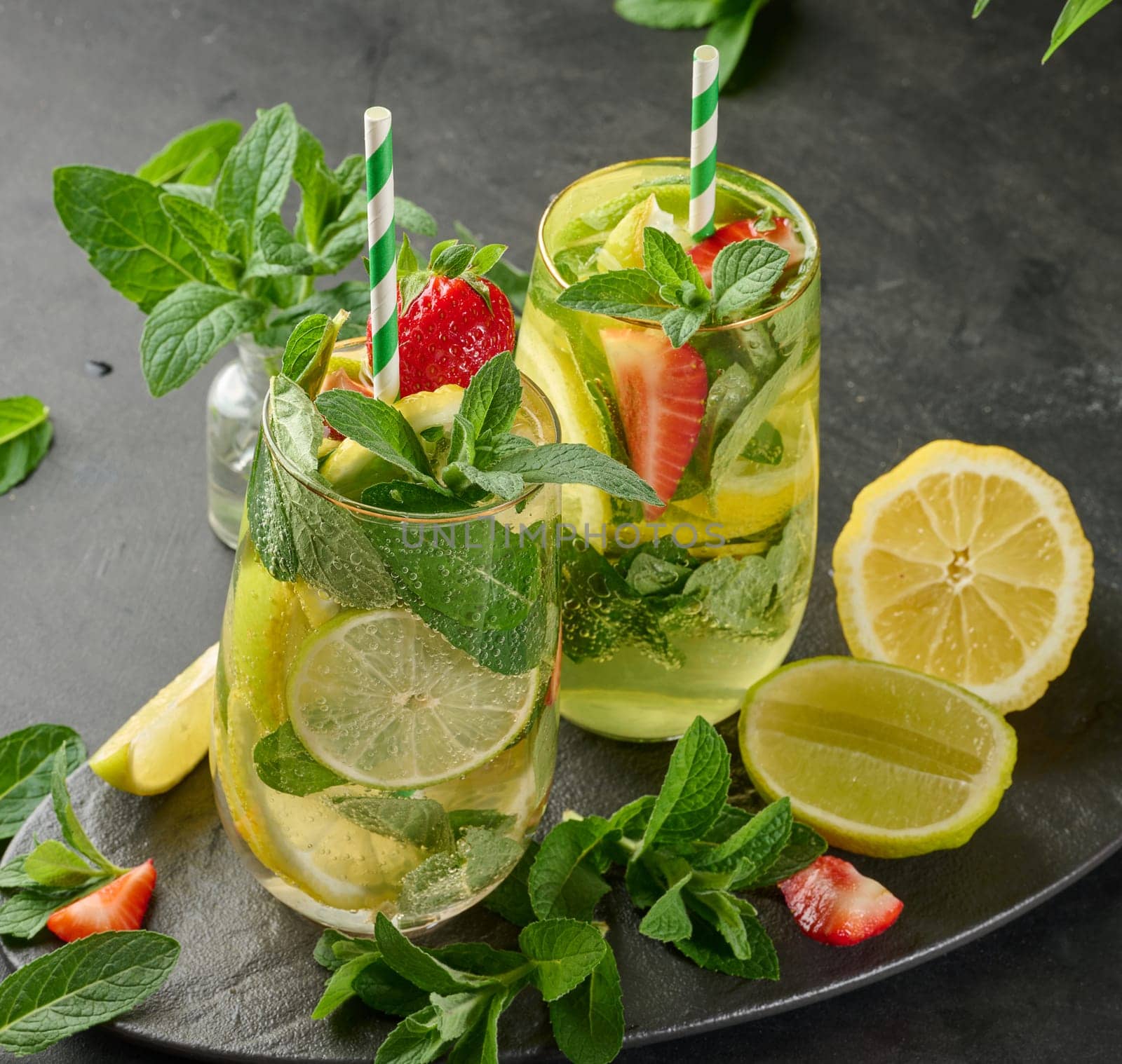 A refreshing drink in a glass with lemon slices, strawberries, fresh mint leaves, and sparkling water, top view