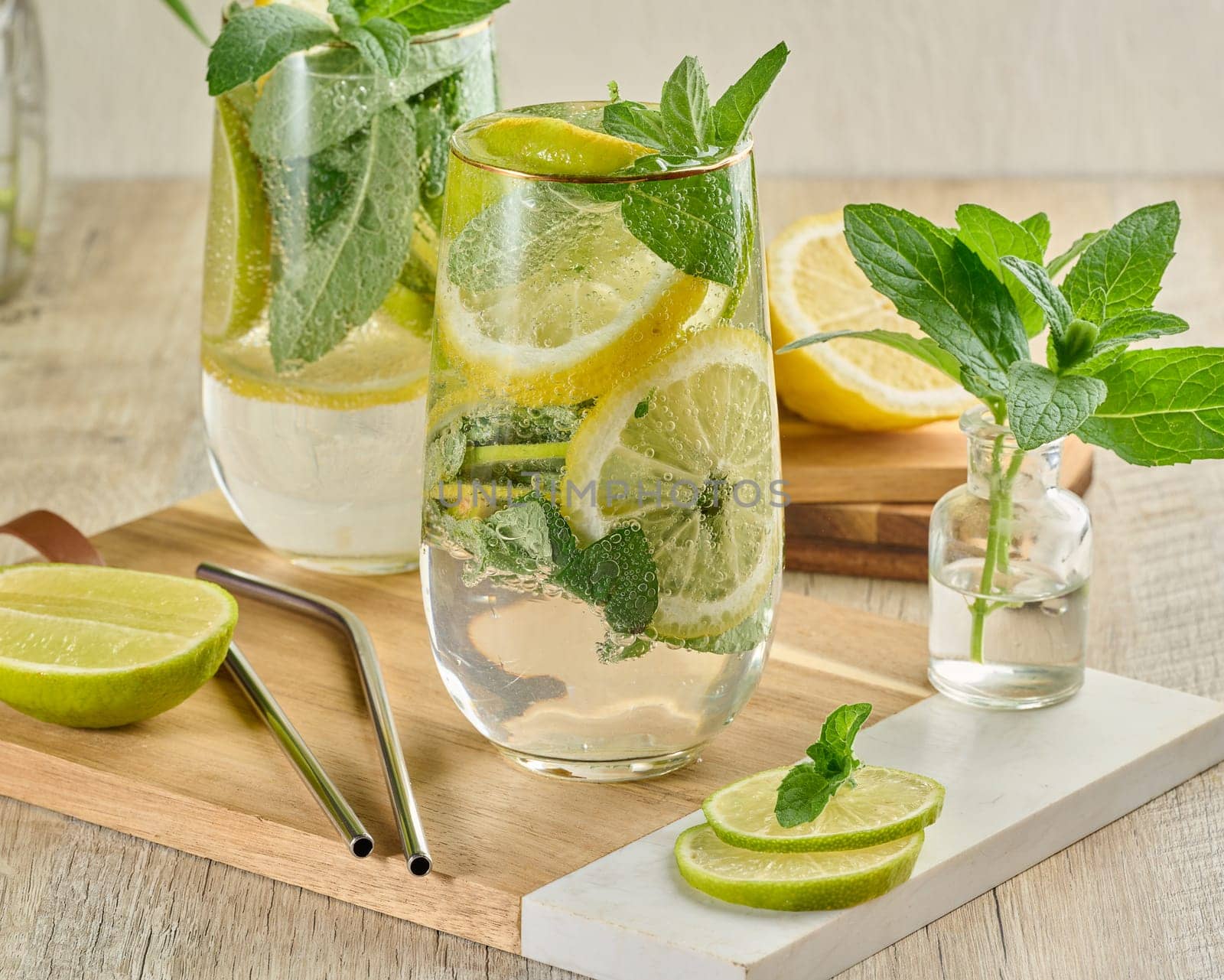 Refreshing citrus and mint drink in glasses with ice, lemon, lime, and mint leaves. Healthy summer beverage