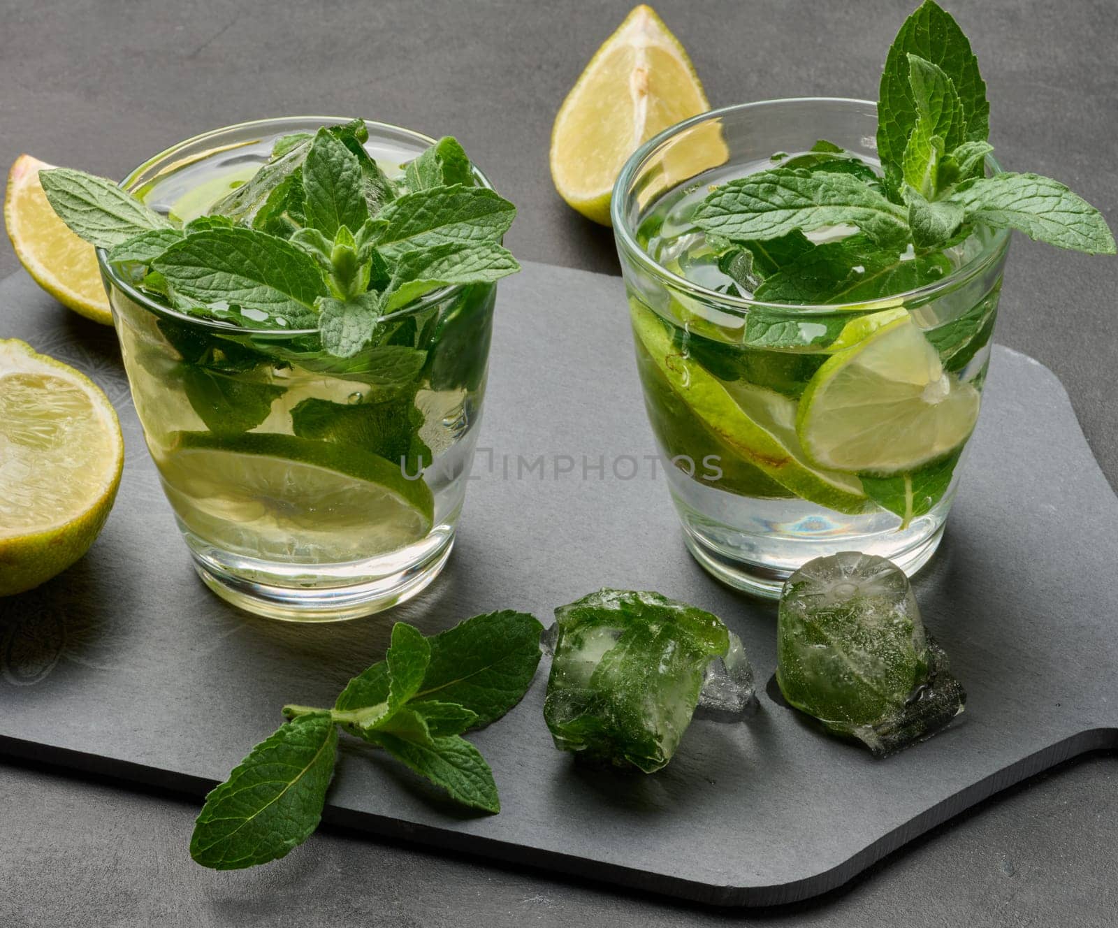Refreshing mojito cocktail with lime, mint, and ice on dark background