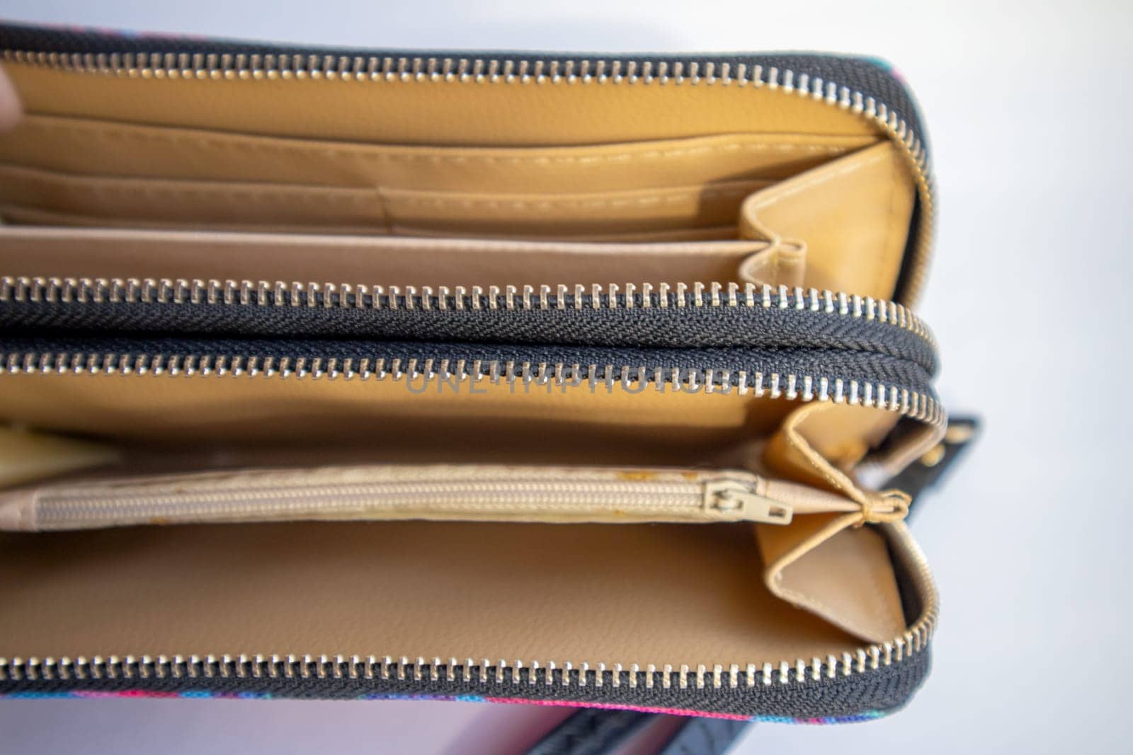 Fashionable outdoor women's empty wallet with gold zippers, top view, on white background.
