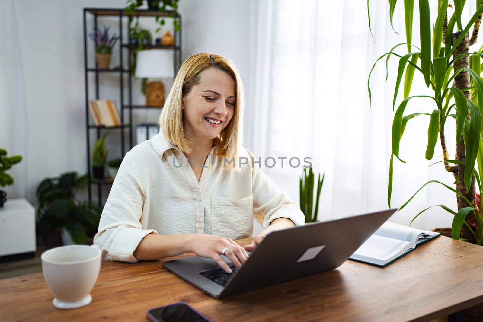 Smiling individual engages with a laptop at a cozy desk