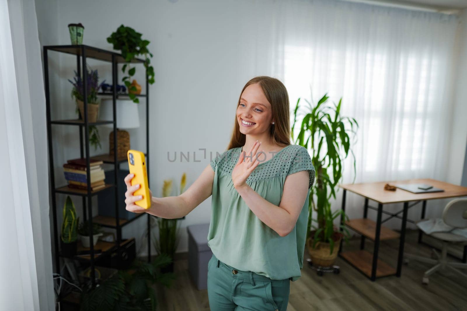 A cheerful woman interacts via video call, embracing connection at home.