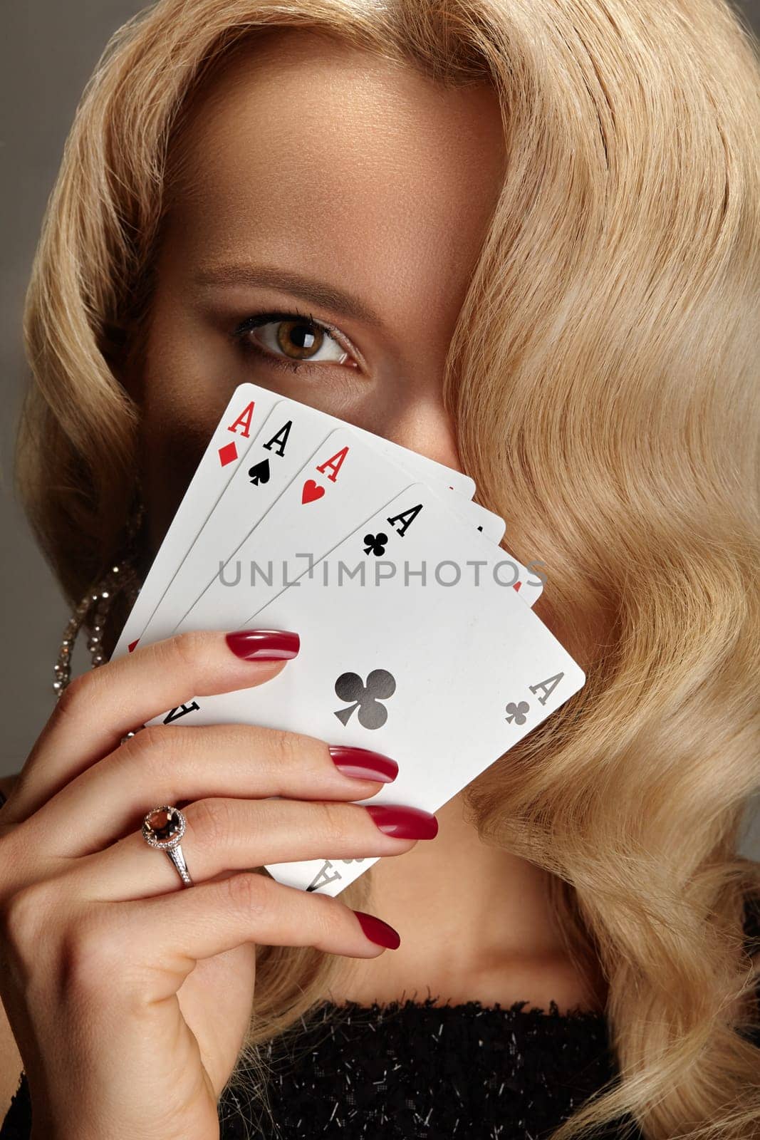 Four aces playing cards in woman's hand. Player with poker quads combination. Elegant female hands with red manicure on nails.