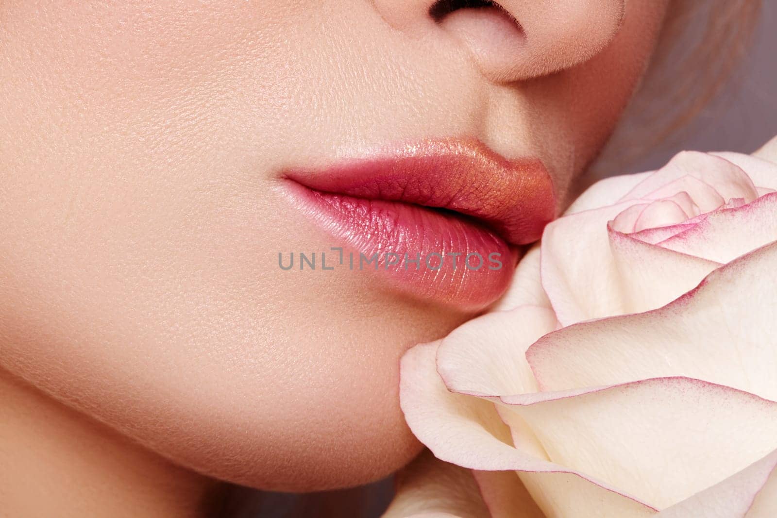 Close-up macro of beautiful female lips with bright kissed makeup. Sexy red lip make-up with gold glitter. Beautiful visage with white rose flower