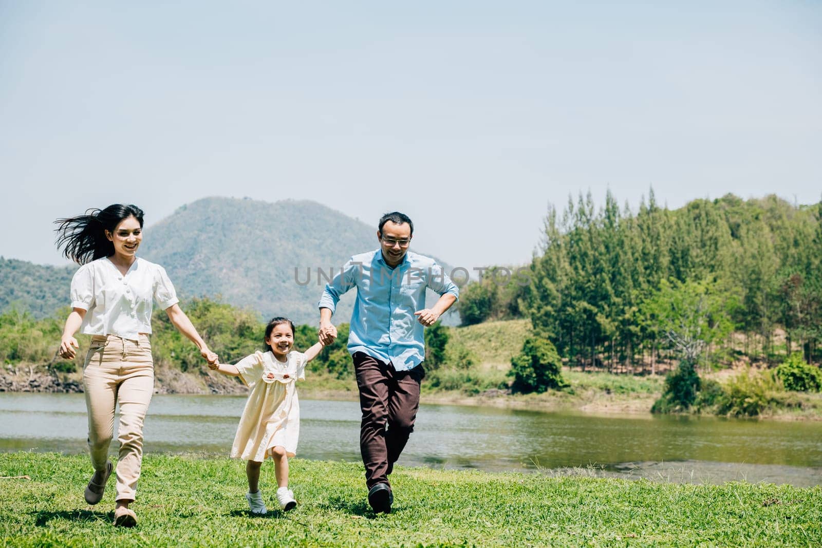 Asian family father mother and daughter holding hands and running lake in park, lifestyle parents and child kid enjoying outdoors together in nature on summer travel, Family relaxation, Front view