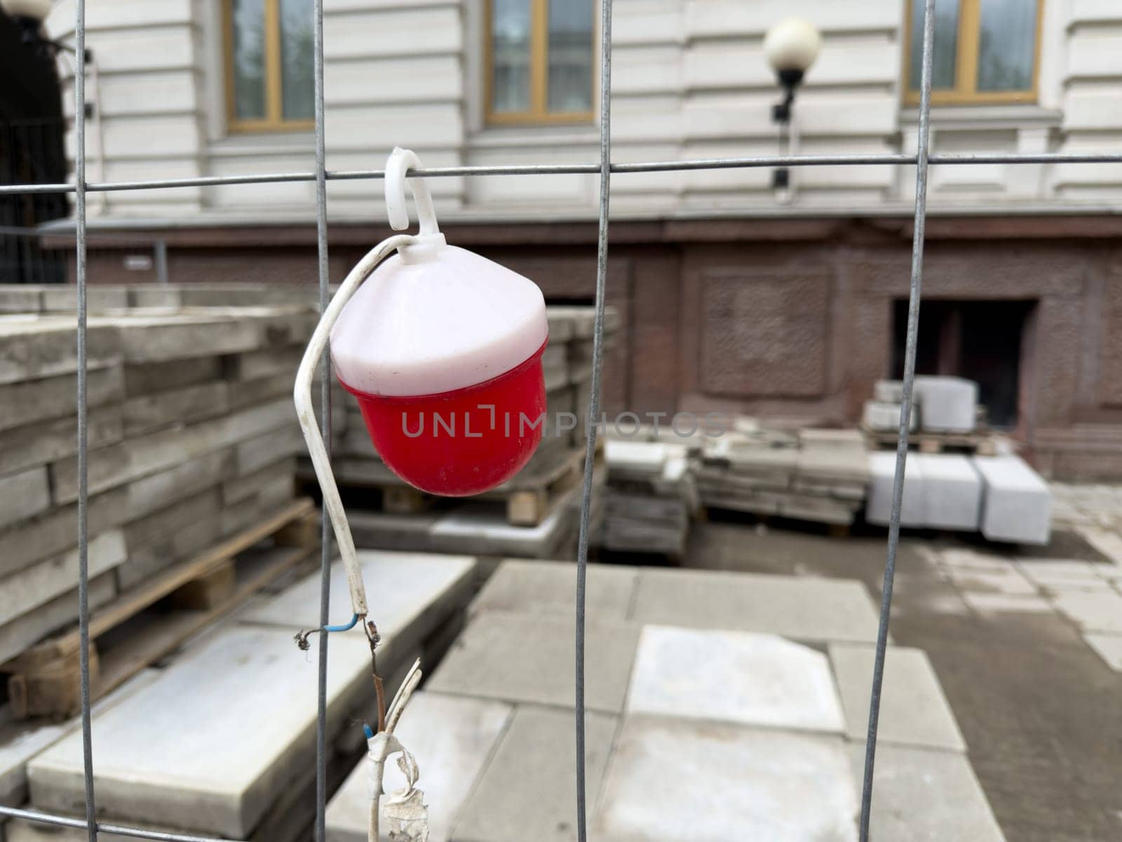 Temporary warning light on construction fence near stacked paving tiles. The image highlights ongoing sidewalk renovation and symbolizes urban development and infrastructure updates