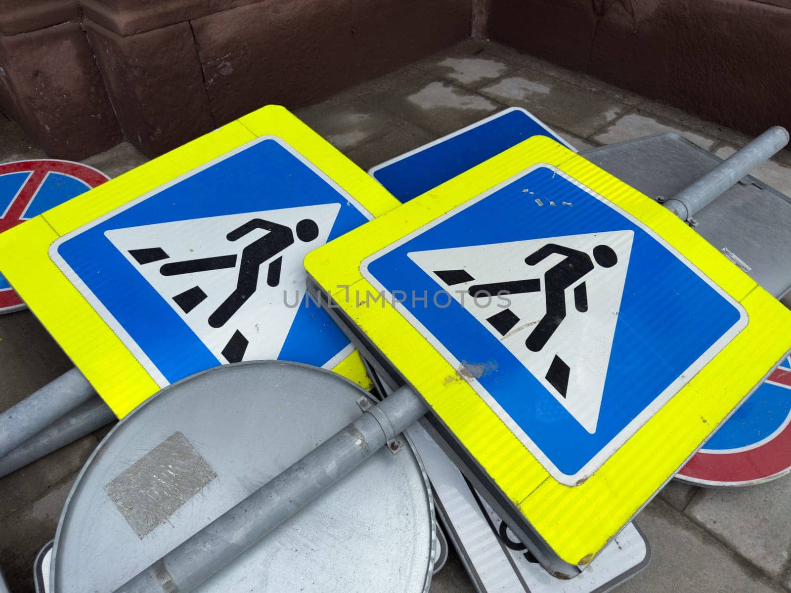 Decommissioned pedestrian crossing signs stacked on the ground as part of an urban infrastructure update. Symbolic representation of modernization and street renovation in the city