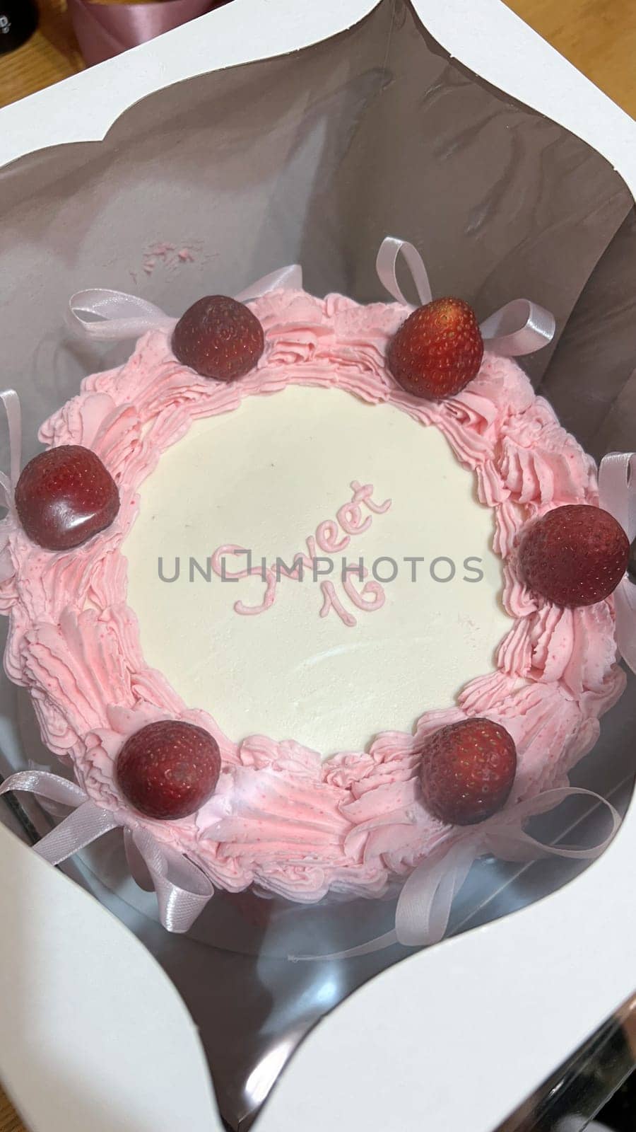 A stunning Sweet Sixteen cake, adorned with fresh strawberries and pink frosting. This elegant cake with ribbon accents is perfect for making any birthday celebration truly special.