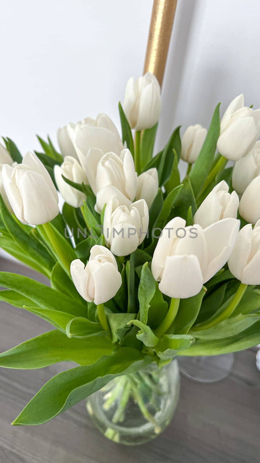 Brighten your space with a beautiful bouquet of fresh white tulips in a clear glass vase. Ideal for home or office decor, this floral arrangement brings elegance and freshness.